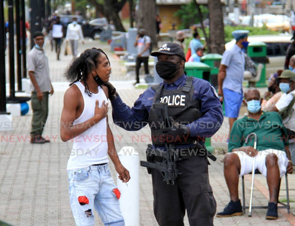 In this file photo, a police officer cautions a pedestrian about wearing a facemask properly along the Brian Lara Promenade, in Port of Spain. - Photo by Ayanna Kinsale