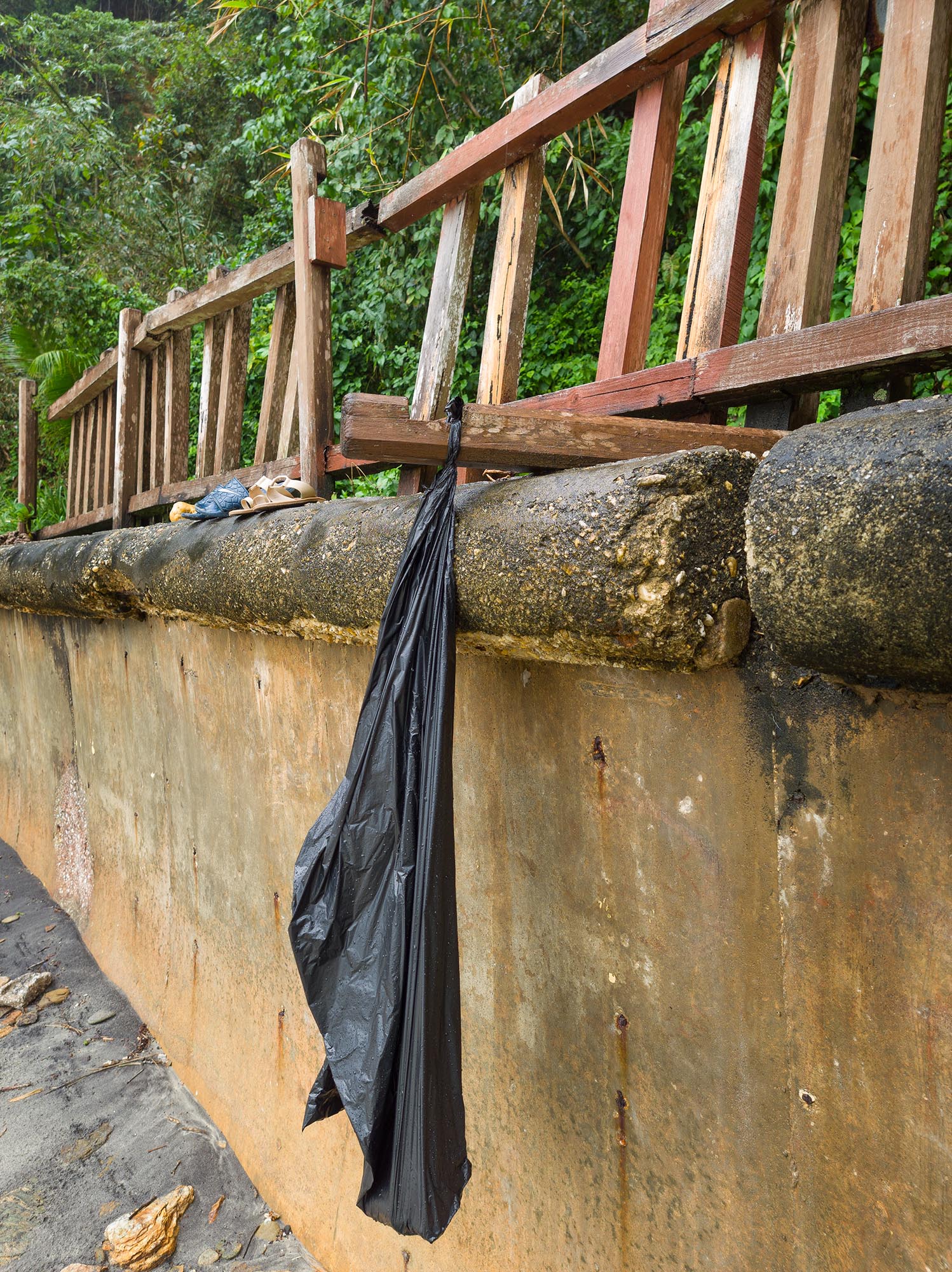 The collapse of the safety features of the beach are now institutionalised, as workers responsible for placing garbage bags for visitor use now hang them from bits of collapsed railing. Photo by Mark Lyndersay.