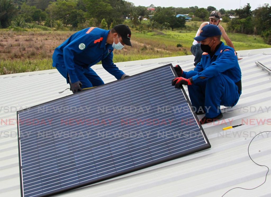 Brothers Sion Faria and Shadrach Faria, co-founders of SOESH, on install a solar panel on a house on Thompson Road, Palmiste. Photo by Roger Jacob
 - 