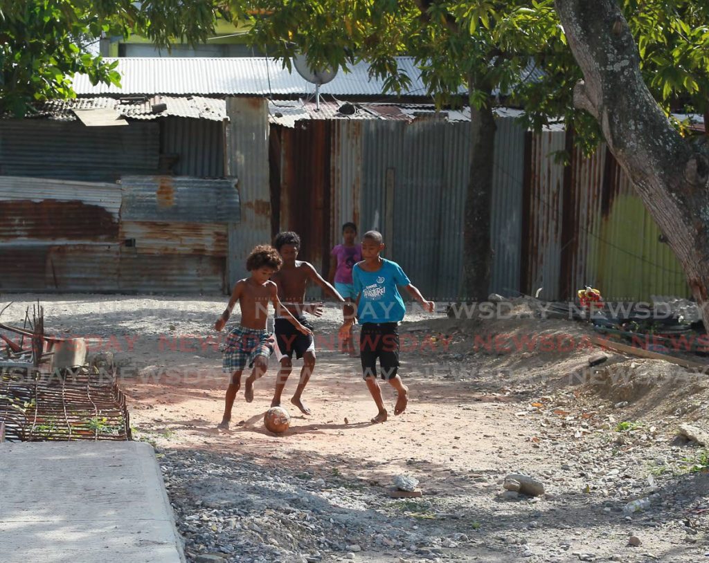 Boys play football in a yard at King's Wharf, San Fernando. Photo by Roger Jacob
 - 