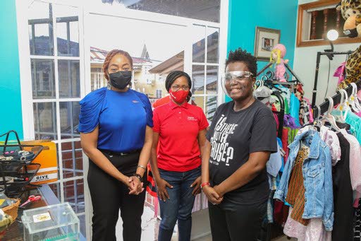 Digicel Foundation CEO Penny Gomez, Digicel Foundation srategic partnership officer Alicia Hospedales and Is There Not A Cause (ITNAC) founder Avonelle Hector-Joseph stand at the new entrance to the thrift shop. - 
