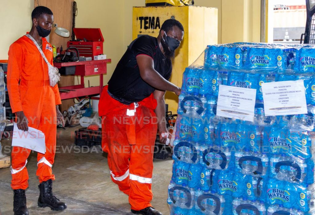 Stephan Mills, right, team leader at TEMA's warehouse, prepares a shipment of water to be delivered to St Vincent. The donation was made by Naseem Smith, principal of School for Children with Special Needs. - David Reid 