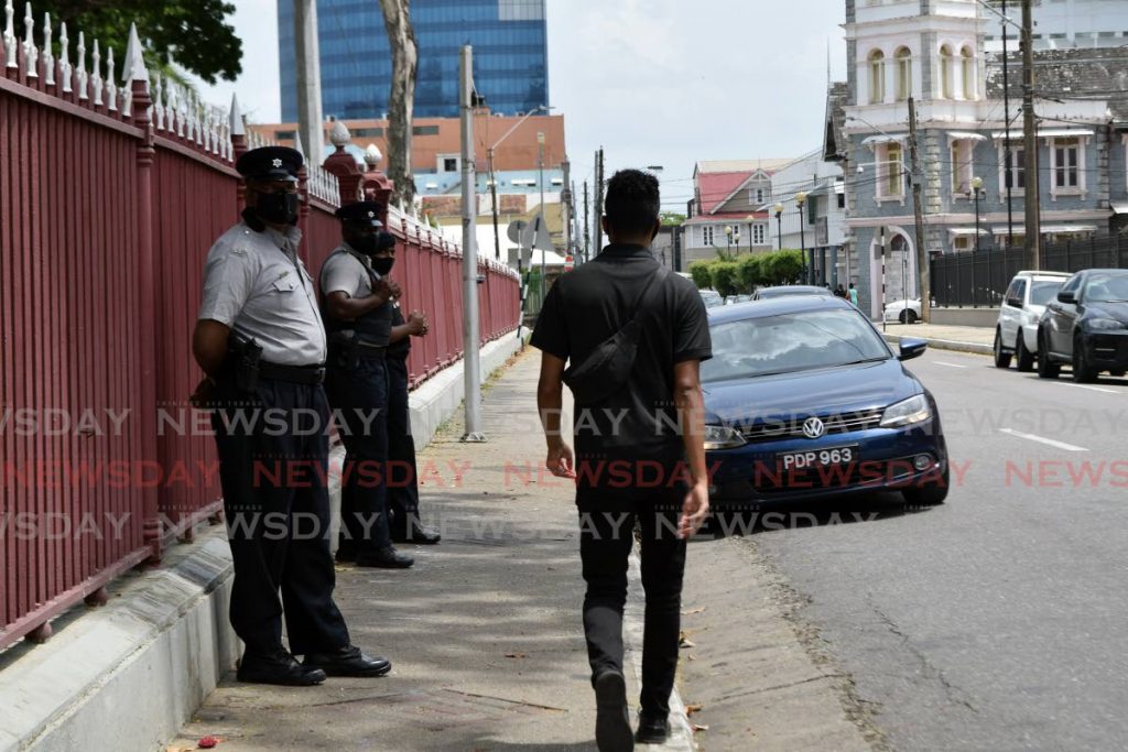 A masked pedestrian walks past police officers outside the Red House. - Vidya Thurab