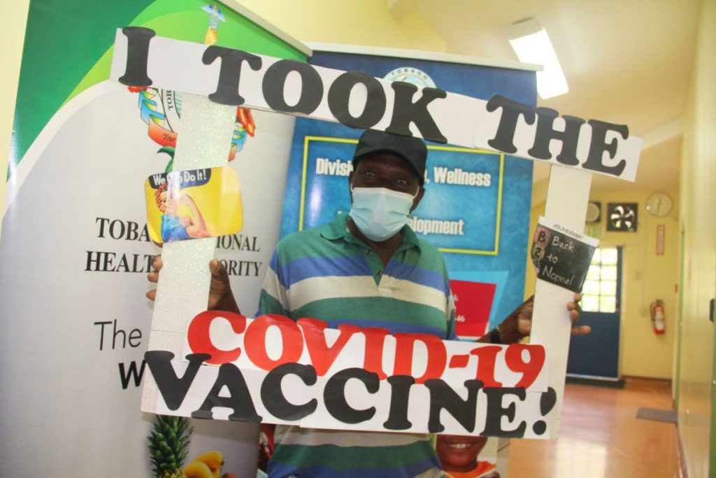 In this photo provided by the Tobago Division of Health, Herman Moses poses with a sign announcing that he took the covid19 vaccine. Moses said, 