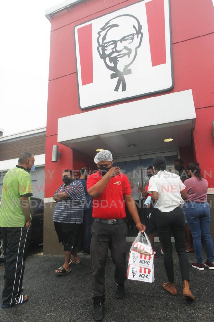 Customers crowd the entrance to the KFC outlet at Gulf View, San Fernando as roll back measures were announed by Prime Minister Dr Keith Rowley on Thursday - Photo by Lincoln Holder