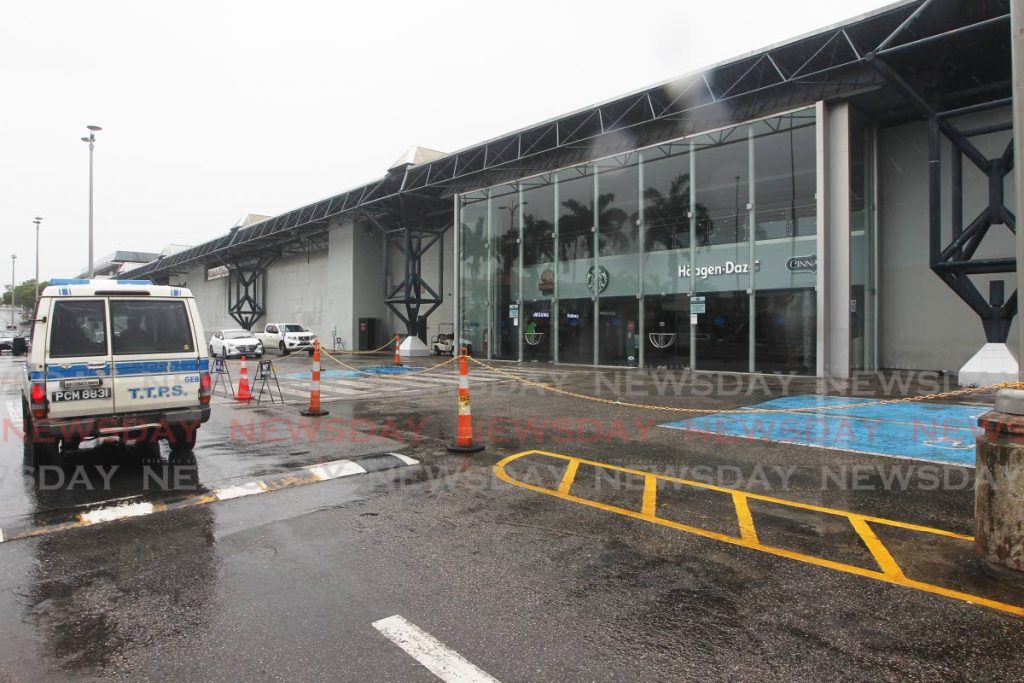 A police van drives past the closed Gulf City mall in La Romaine on Friday. - Photo by Lincoln Holder