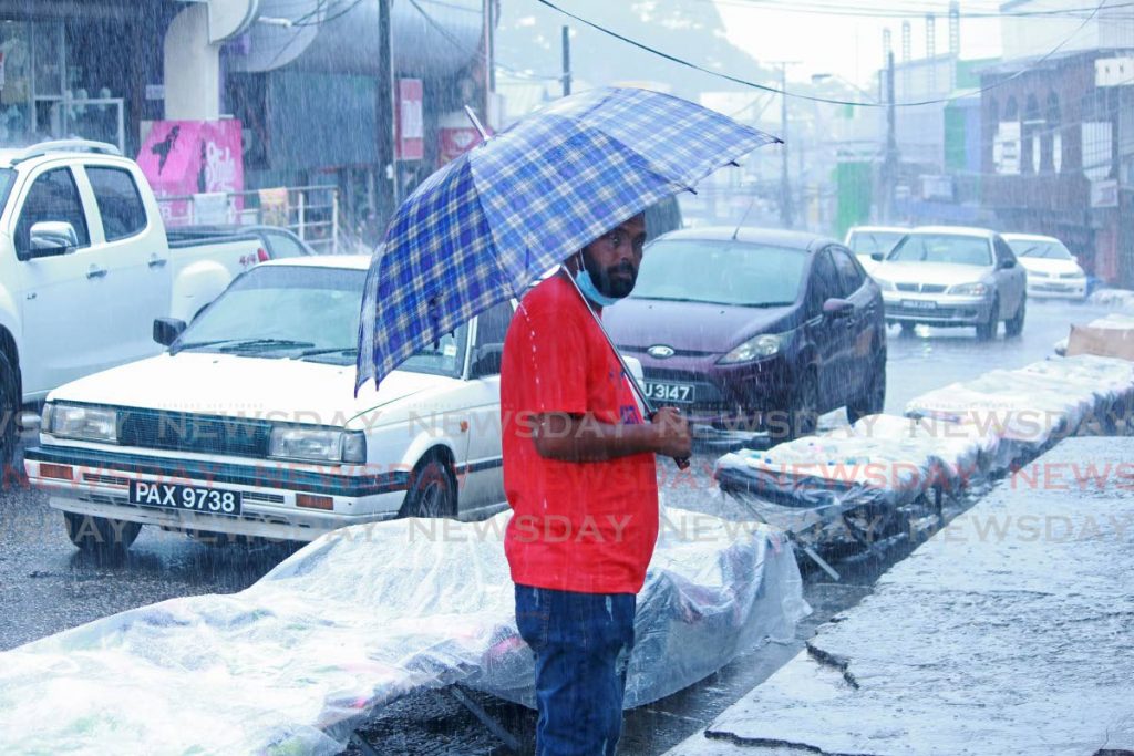 A man shelters under an umbrella during heavy rainfall on High Street, San Fernando. - CHEQUANA WHEELER