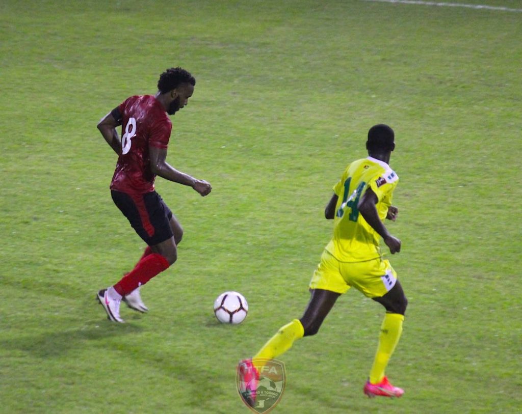 In this photo taken on March 25, 2021, TT captain Khaleem Hyland (left) moves past Guyana midfielder Daniel Wilson during the 2022 FIFA World Cup Concacaf Zone qualifier at the Estadio Panamericano, San Cristobal, Dominican Republic. PHOTO COURTESY TTFA. - 