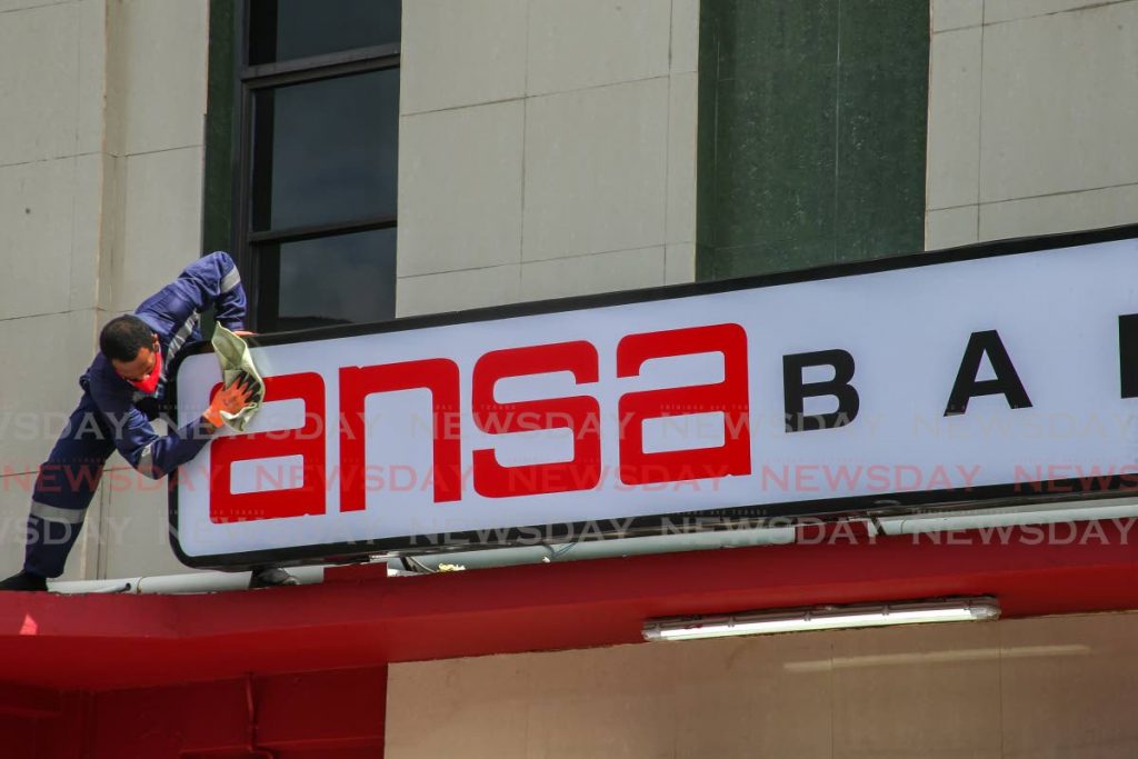 A worker affixes signage on a branch of Ansa Bank ahead of its opening in April. - Jeff K. Mayers  