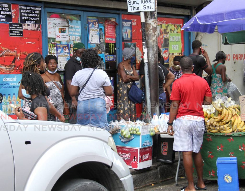 Customers, some not wearing masks, wait to enter a grocery on Charlotte Street, Port of Spain on Friday. - PHOTO BY AYANNA KINSALE
