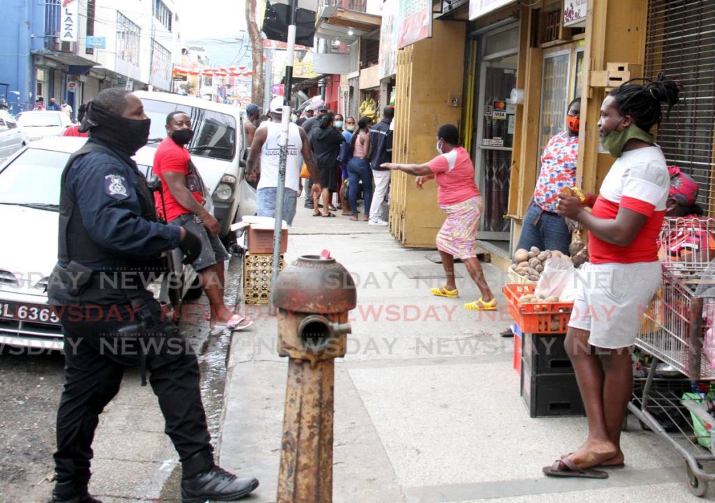 Police caution a man on Charlotte Street, in Port of Spain who was eating on the sidewalk with his facemask pulled down. - Photo by Ayanna Kinsale