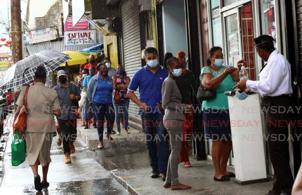 SANITISING: A security guard outside the Pennywise branch on Charlotte Street in Port of Spain ensures customers wear their maskes and also sanitise their hands before entering the businessplace. PHOTO BY SUREASH CHOLAI - 