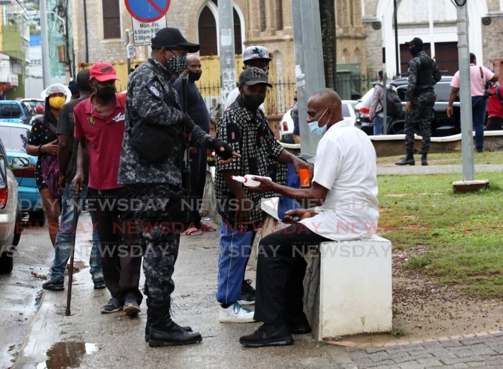 A police officer on patrol speaks to a man seated along the Brian Lara Promenade on Friday. - SUREASH CHOLAI