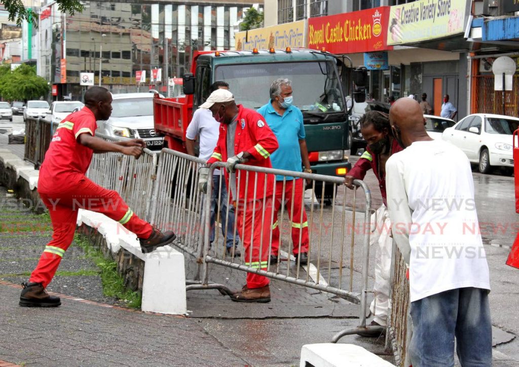 Employees from the Port of Spain Corporation employess place barriers around the Brian Lara Promenade in Port of Spain on Saturday, to prevent citizens from gathering. - Angelo Marcelle