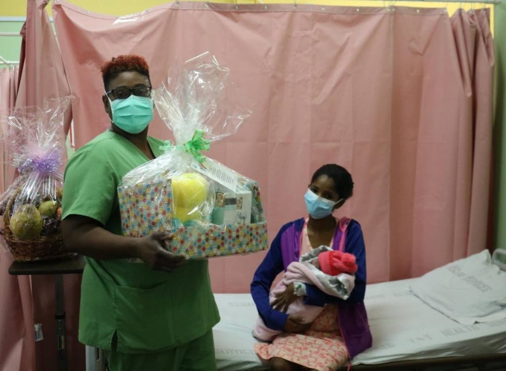 Ellen Campbell, acting head nurse and midwife, presents a hamper and fruit basket to Amanda Mohammed, first mother to give birth at the Sangre Grande Hospital on Mother's Day. PHOTO COURTESY ERHA - 