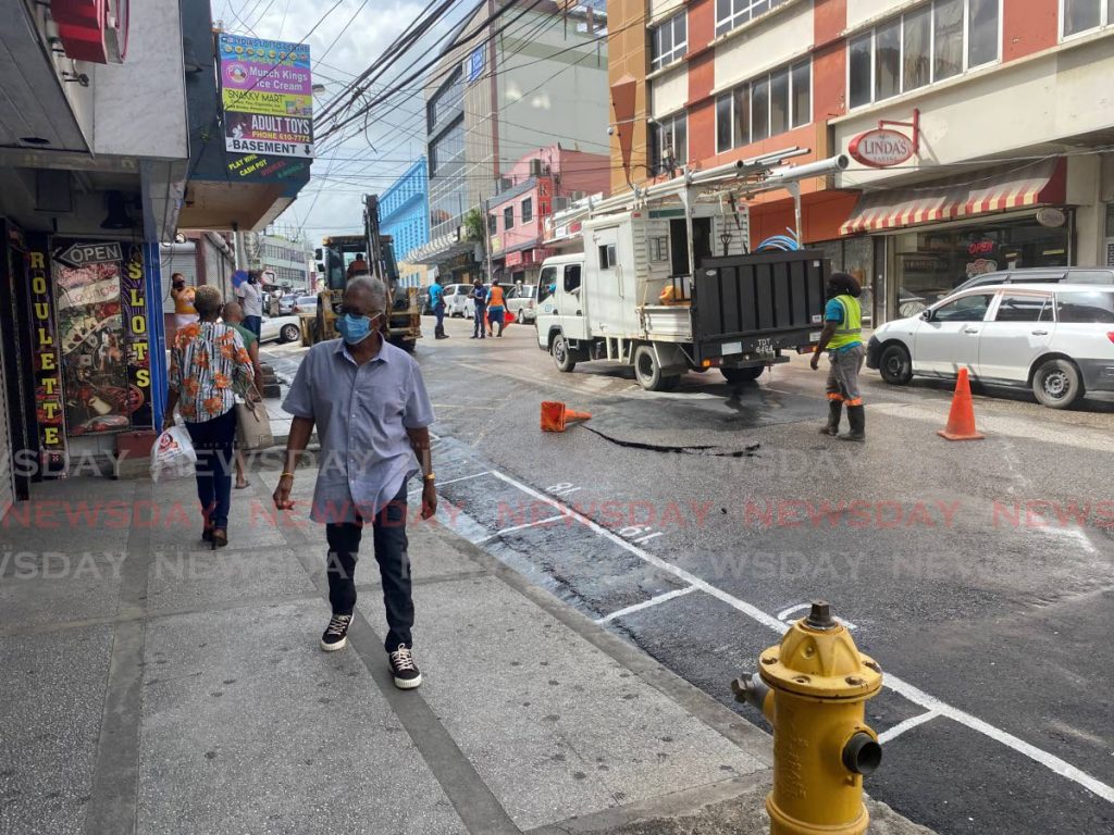 WASA workers at High Street, San Fernando where the main pipeline burst and caused minor flooding on Tuesday morning.  - Narissa Fraser