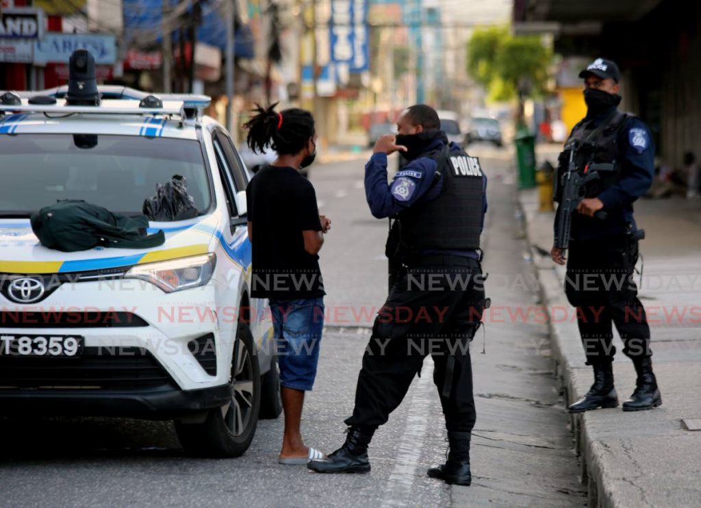 Police officers stop and search a pedestrian on Frederick Street, Port of Spain on Saturday. Instances like this are expected to increase in the coming days.  - SUREASH CHOLAI