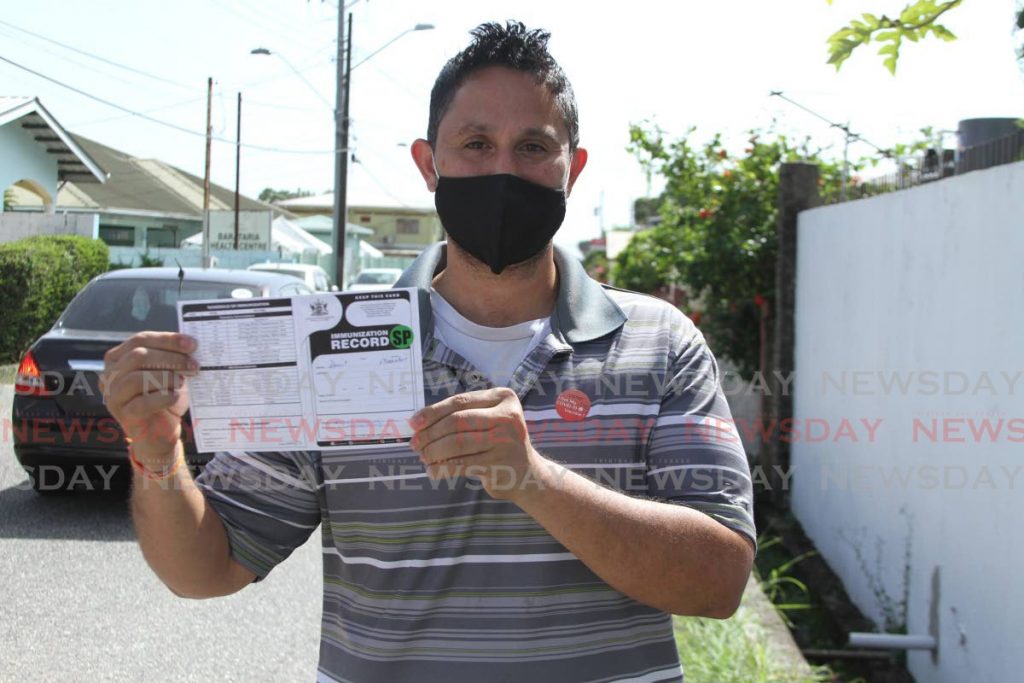 St Augustine resident Amrit Mahabir displays his vaccination card after getting the Sinopharm vaccine at the Barataria Health Centre on Monday. - Marvin Hamilton