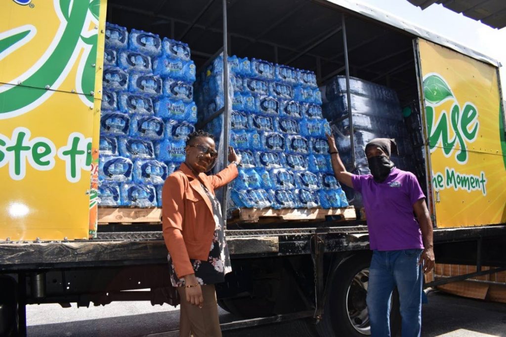 HELPING HAND: Cpl Gomes of the TTPS, left, receives some of the Blue Waters Ltd products. At right is a Blue Waters delivery agent. Photo courtesy- Blue Waters Ltd