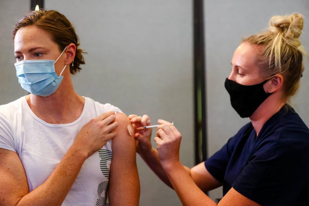 Three time Olympian, Australian swimmer Cate Campbell (left), receives her dose of Pfizer/BioNTech vaccine against covid19 at the Queensland Sports and Athletics Centre in Brisbane on May 10, after the Australian Olympic Committee began their rollout of vaccinations for members of the Olympic team ahead of the Games in Tokyo. (AFP PHOTO) - 