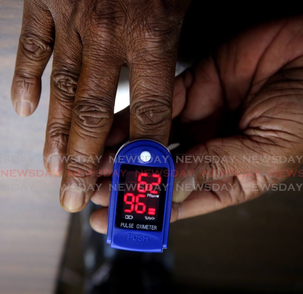 A patient measures his blood oxygen levels with a pulse oximeter distributed by MTR Investments Ltd of Curepe. - SUREASH CHOLAI