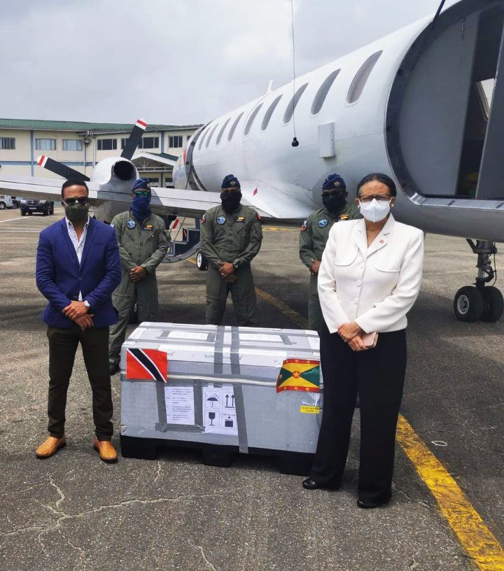 FROM GRENADA, WITH LOVE: Foreign and Caricom Affairs Minister Dr Amery Browne, left, the three TT Air Guardsmen and TT's Ambassador to Caricom Frances Seignoret with the container carrying the 10,000 doses of covid19 vaccines which arrived in Trinidad on Sunday from Grenada. PHOTO COURTESY MINISTRY OF FOREIGN AND CARICOM AFFAIRS.  