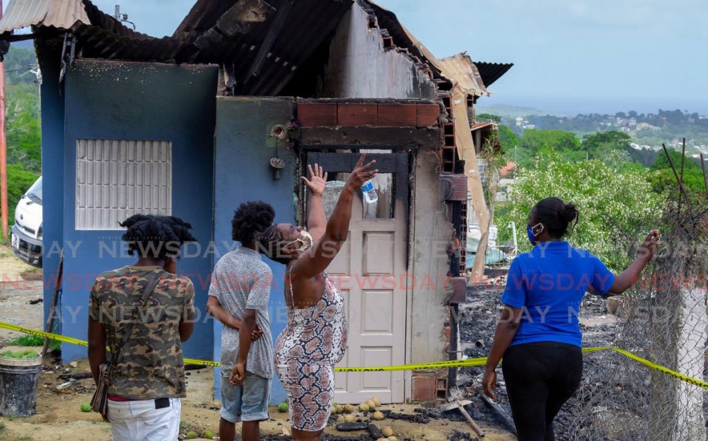 SORROW: Margaret Seaforth gestures to the heavens as she and other relatives stand outside her home in Union Village Street, Tobago which was gutted by fire. PHOTO BY DAVID REID - 