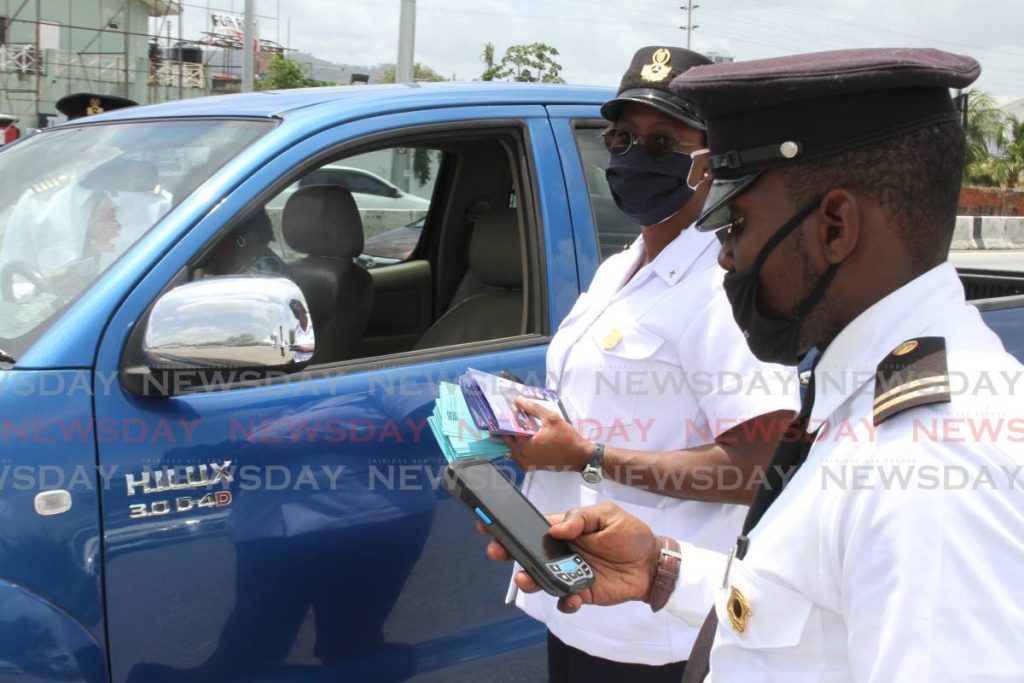 FILE PHOTO: Licensing Officers check information about a driver, on their mobile handheld ticketing device, at the launch of the demerit point and traffic ticketing system in Port of Spain last May. - 