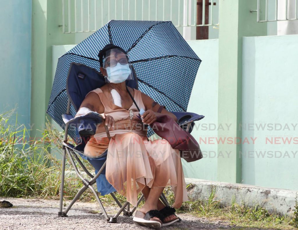 WAITING PATIENTLY: Carol Grandier, 77, arrived just after 5am at the Barataria Health Centre to recieve her covid19 vaccine. She was given the number 24 by a security guard on duty.  - Photo by Roger Jacob