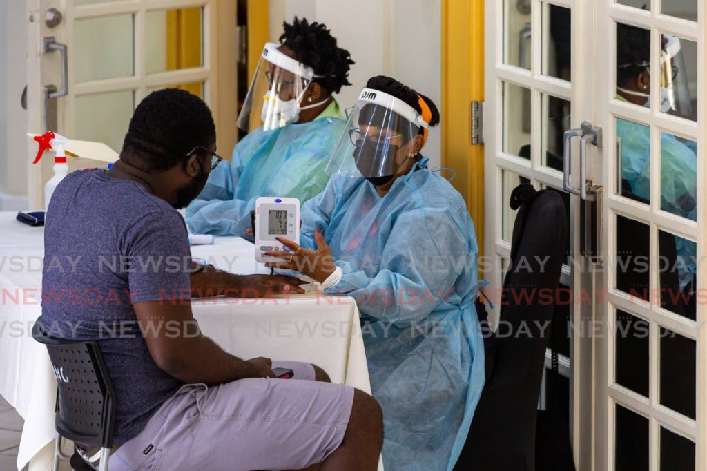 Nurses check the vitals of a man on Saturday during a vaccination drive for construction workers and Magdalena Grand Beach and Golf Resort employees at Magdalena, Lowlands.  - Photo by David Reid