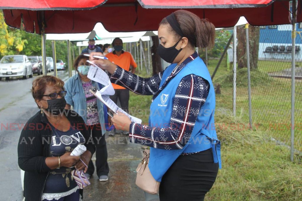 ORDERLY MOVE: An SWRHA employee checks the information provided by people waiting to enter the La Romaine Health Centre on Thursday to get their covid19 vaccination. Photo by Lincoln Holder - 