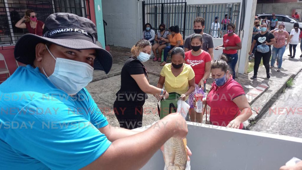 Carlos Hernandez during distributes free fish in front of the La Casita building on Farfan St in Arima. More than 100 people were able to receive a bag of cro-cro fish and a cornmeal. - Grevic Alvarado