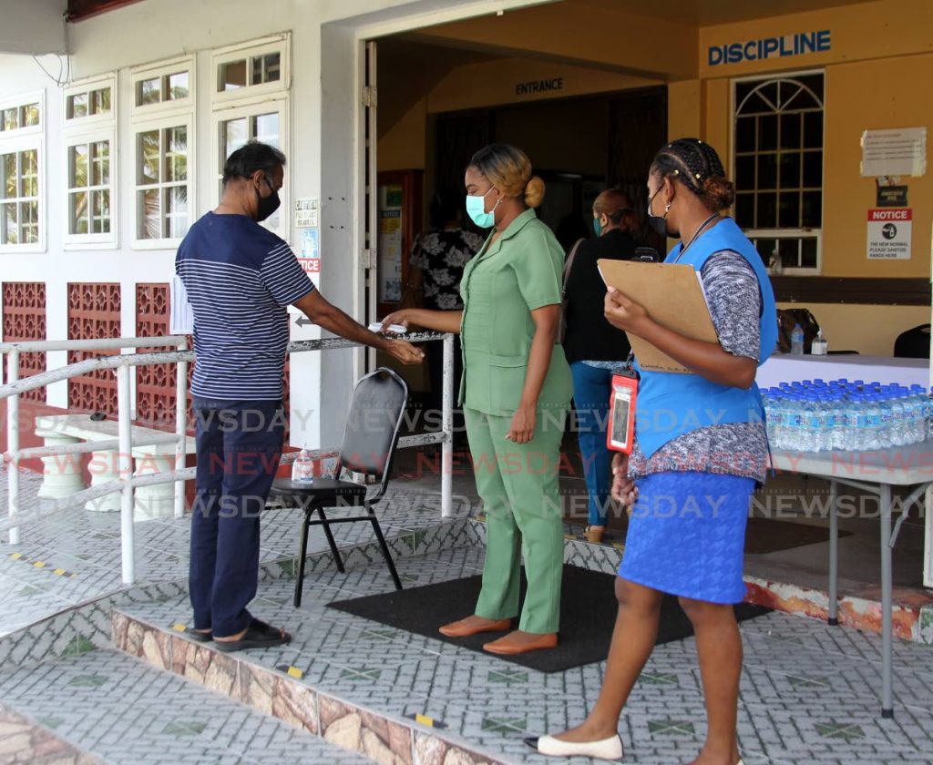 Staff at the Sangre Grande Civic Centre screen people arriving for their vaccine. Photo by Roger Jacob