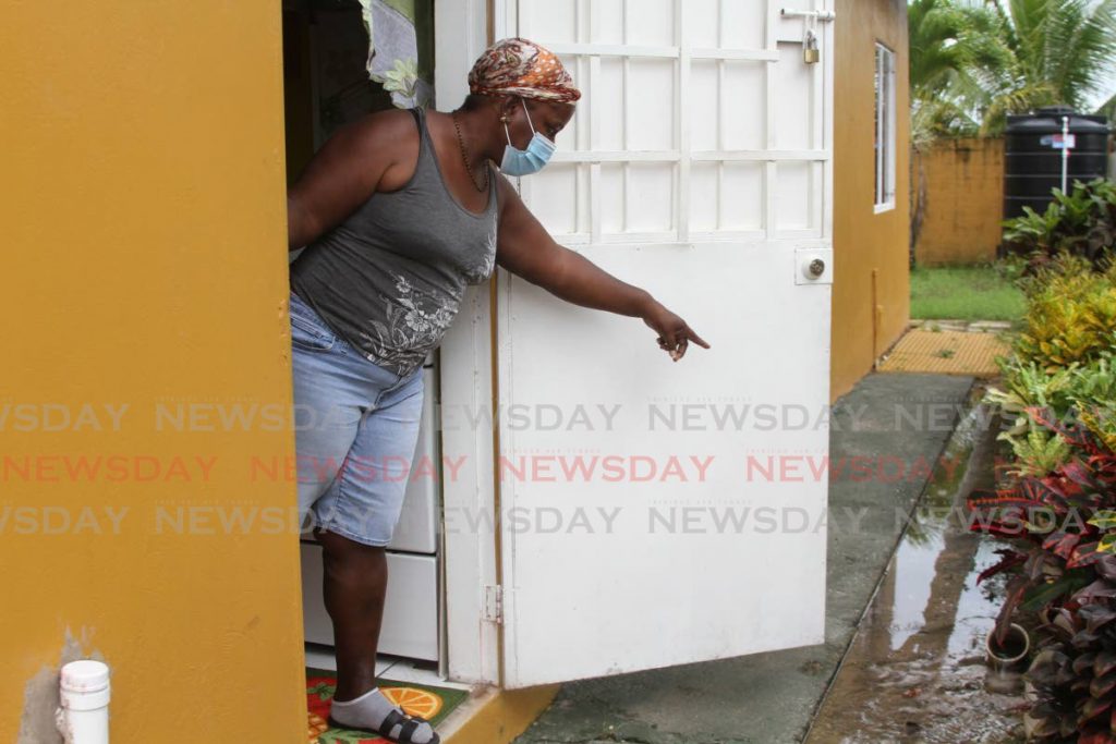 THERE: In this file photo HDC tenant Nicole De Silva points to the drain at side of her Demerara Heights, Wallerfield home which is filled with water from a nearby leaking sewage line. She said the leak has been there since 2008. Photo by Marvin Hamilton 