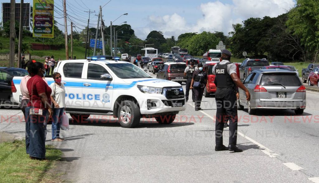 People wait for transportation alongside the San Fernando By-Pass on Friday, after they were turned away from receiving hampers at the South Park Mall owing to the large crowd which showed up. - Angelo Marcelle