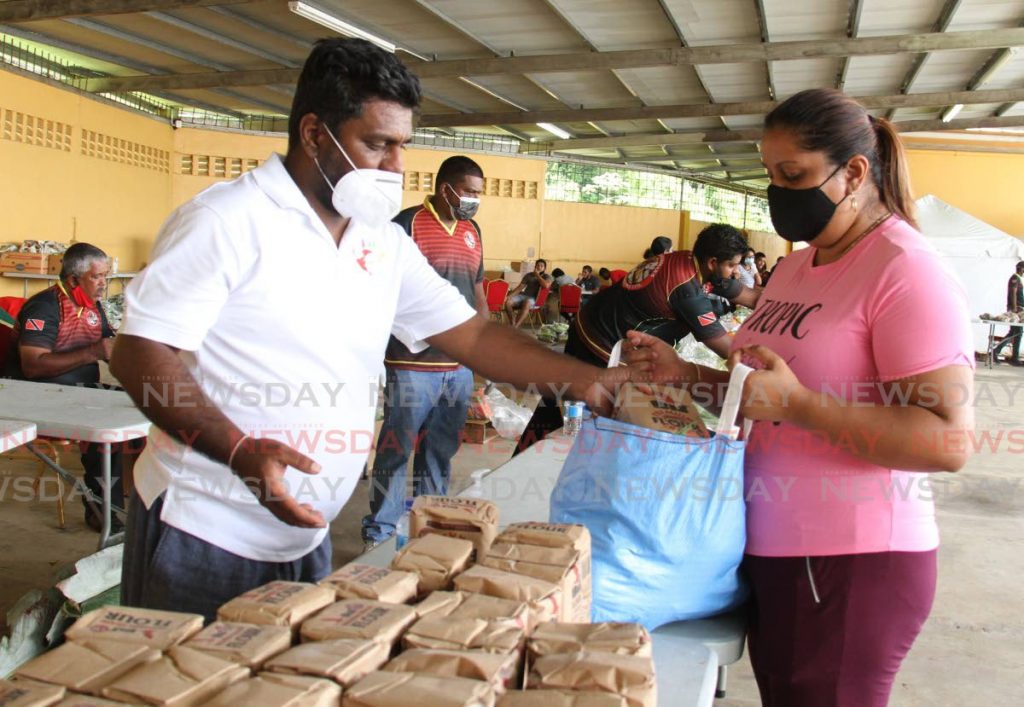 HELPING HAND: Attorney Gerald Ramdeen assists a recipient at the fresh produce food bank and mini-supermarket he hosted at Jaggasar Company Agency Ltd in Penal. The distribution of hampers was held on both Saturday and Sunday. PHOTO BY AYANNA KINSALE - 