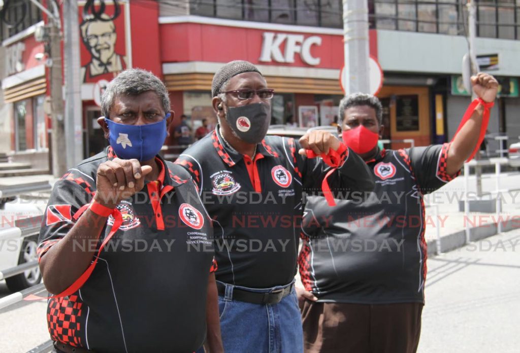 Members of the Trinidad and Tobago Taxi Driver's Network hold their fists up with red ribbons tied around the duing a press conference on High Street, San Fernando. Photo by Ayanna Kinsale