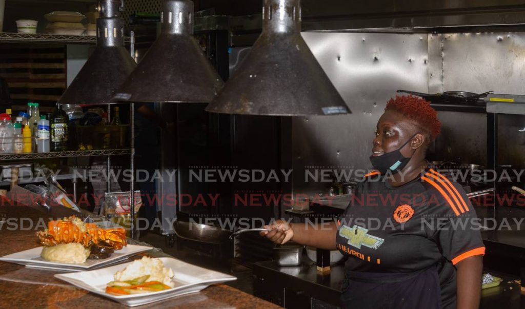 In this November  21, 2020 file photo chef Candis Williams prepares a meal at Waves Restaurant in Tobago. From July 19 restaurants can partially reopen with curbside and takeaway services only.  - 