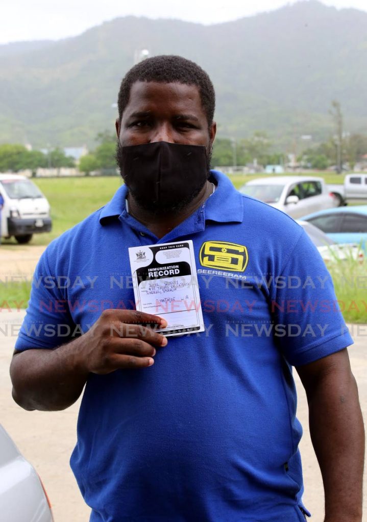 Seereeram Brothers employee Akiel Woodley holds his immunization card showing he got the covid19 vaccine at the National Racquet Centre,Tacarigua. Vaccine passports will require travellers to show proof of being vaccinated against covid19. - Photo by Sureash Cholai