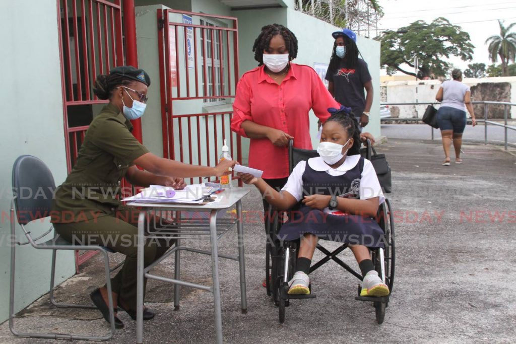 An SEA student checks with security as she enters the Tranquility Government Secondary School before the start of exams on Thursday. - Marvin Hamilton