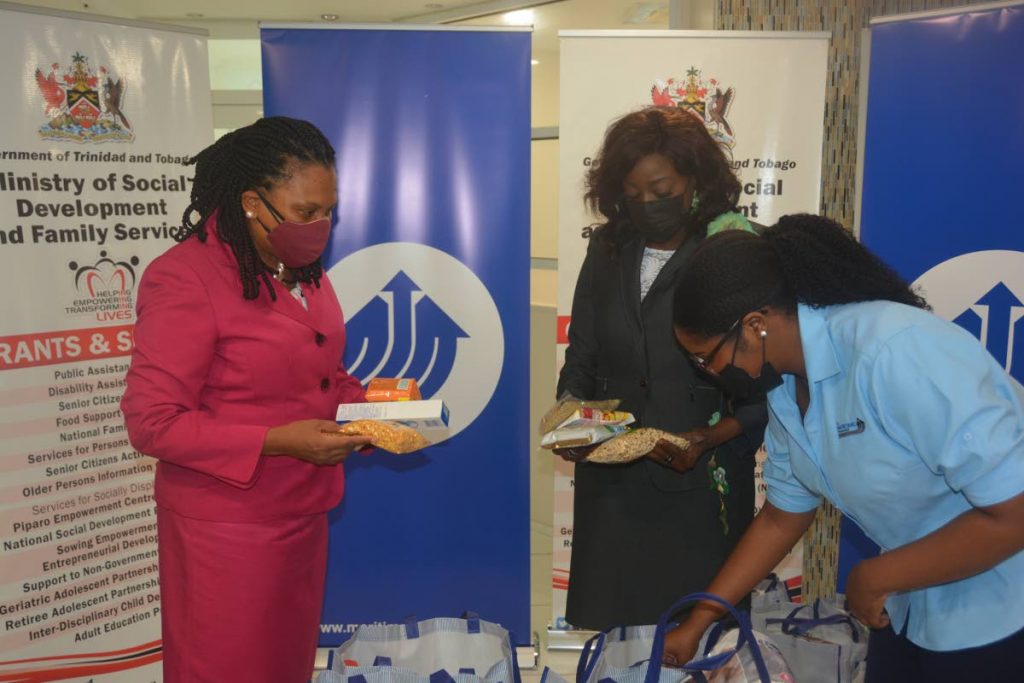 Minister of Social Development and Family Services Donna Cox and permanent secretary Jacinta Bailey-Sobers view the various goods inside each hamper. At right is Maritime Financial Group representative Shania Gloudon. - MINISTRY OF SOCIAL DEVELOPMENT AND FAMILY SERVICES
