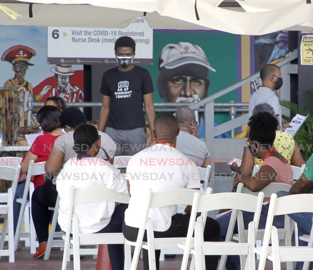 A volunteer provides an update to people in the construction sector waiting to get their second dose of Sinopharm vaccines at Queen's Park Savannah, Port of Spain on Saturday. The vaccination programme will be expanded to the private and social sectors, Government announced. - PHOTO BY ROGER JACOB