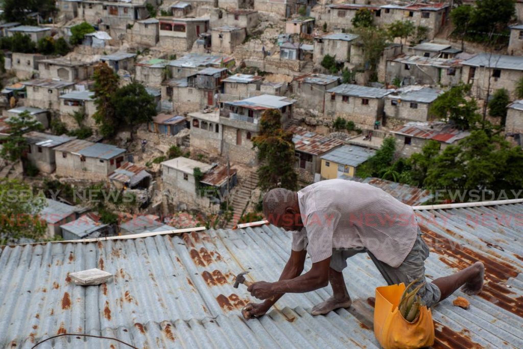 Antony Exilien secures the roof of his house in response to Tropical Storm Elsa, in Port-au-Prince, Haiti, on Saturday. AP Photo/Joseph Odelyn. - 