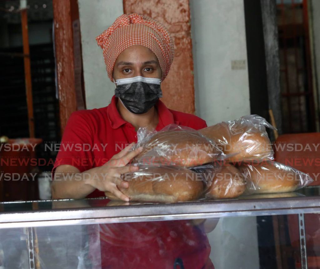 An employee places bread on a counter for sale at Chee Mooke Bakery in Port of Spain.  Photo by Sureash Cholai