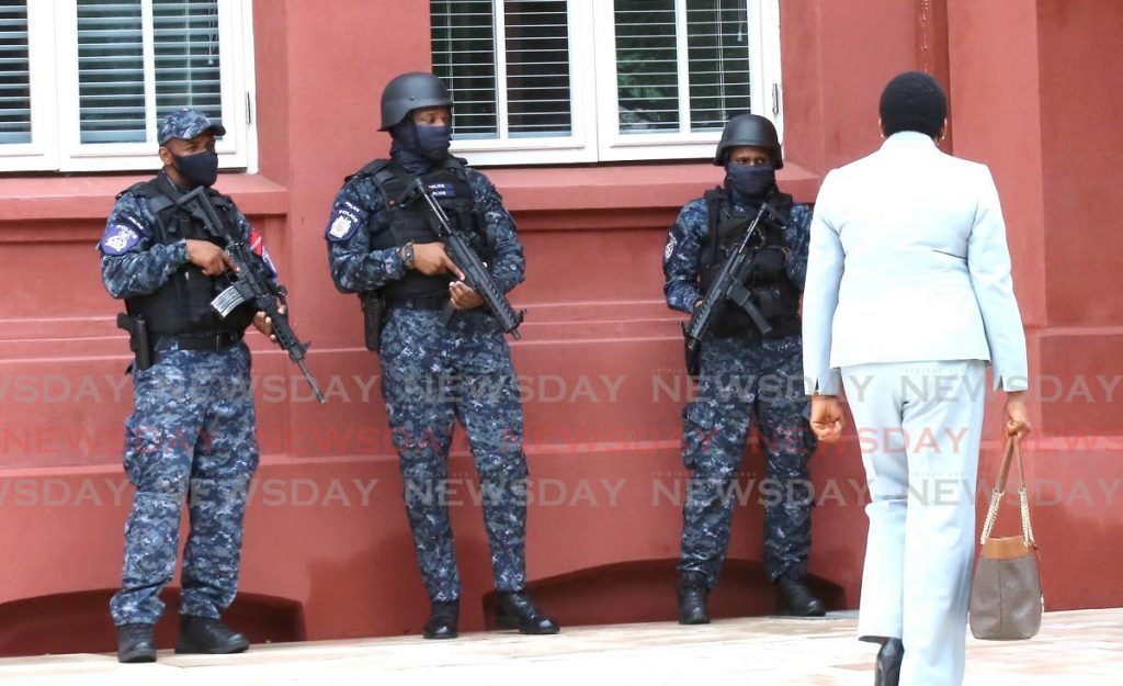 Heavily armed police officers stand guard as Housing Minister Pennelope Beckles makes her way to Parliament at the Red House, Port of Spain on Friday. - Photo by Sureash Cholai