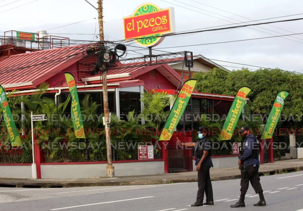 Police officers outside El Pecos on Ariapita Avenue, Woodbrook on Friday. The restaurant which reopened on Thursday as a supermarket but sold prepacked meals closed on Saturday. - Photo by Sureash Cholai