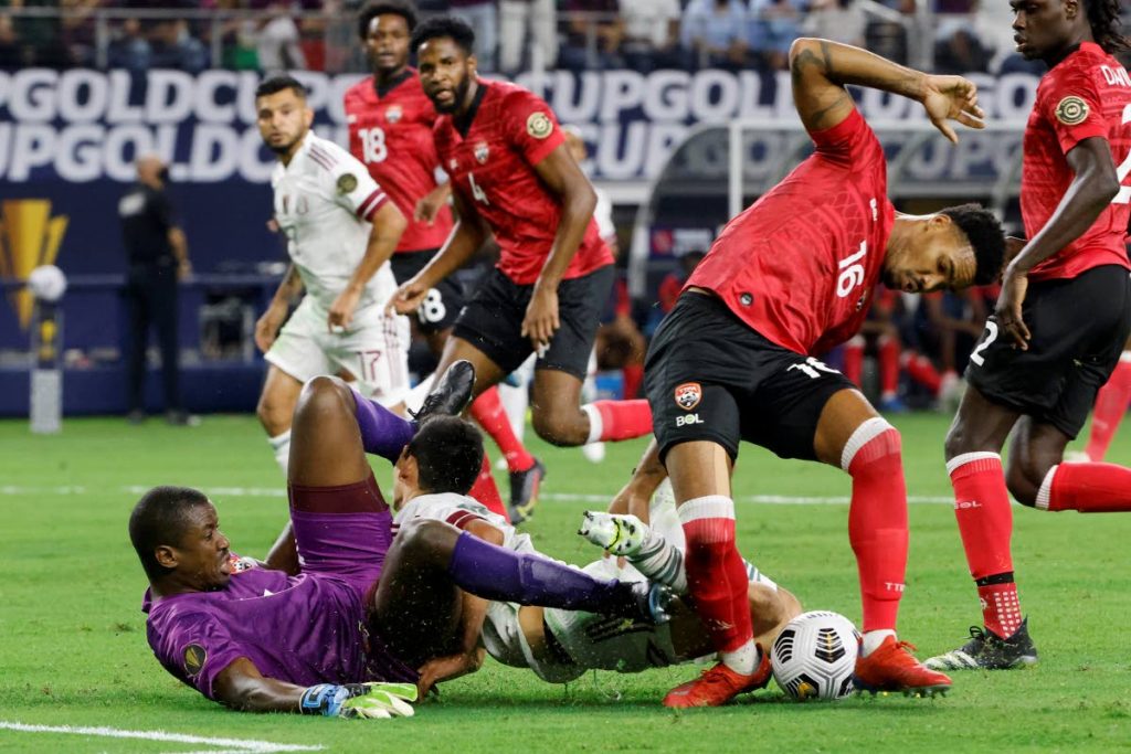 Trinidad and Tobago goalkeeper Marvin Phillip, bottom left, slides into Mexico forward Hirving Lozano, centre, as defender Alvin Jones (16) defends during the first half of a Concacaf Gold Cup Group A match in Arlington, Texas, on Saturday. (AP Photo) - 