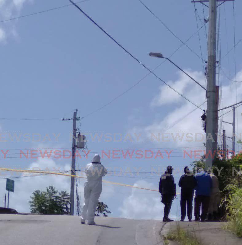 CRIME SCENE: Police at crime scene officers at Arima Old Road on Wednesday morning after three people including a woman and her son were found shot to death. Photo by Shane Superville