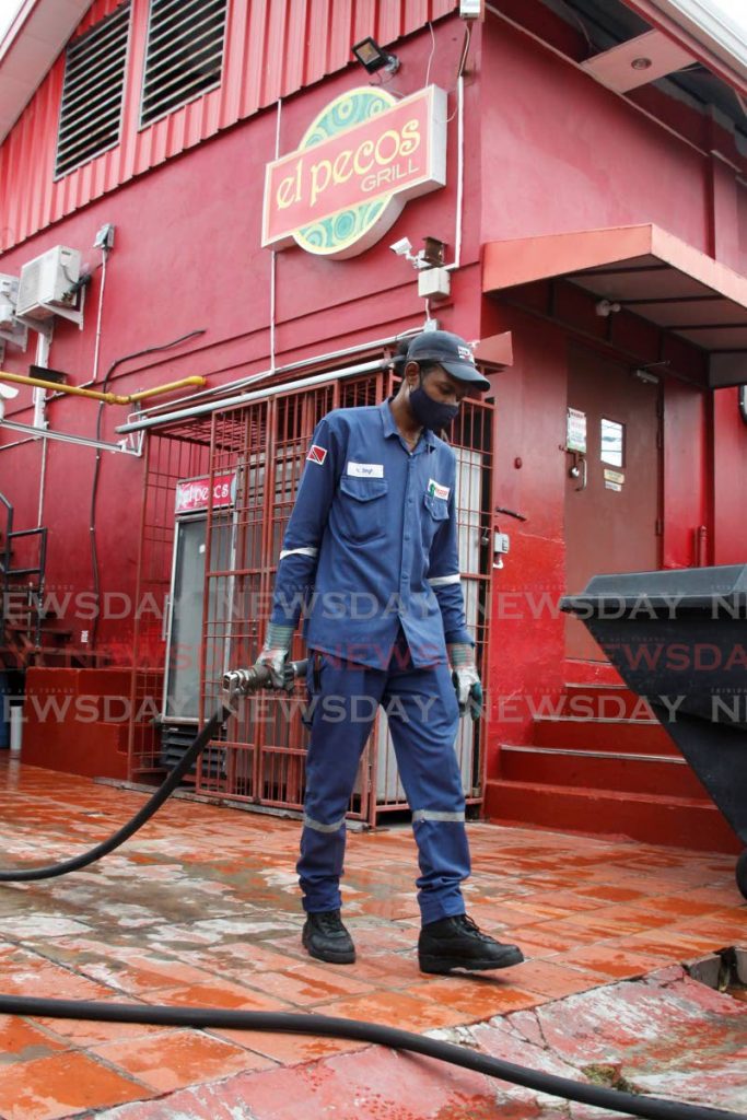 Ramco fuel technican Nester Singh guides the supply hose during his fuel delivery To El Pecos Grill on Ariapita Avenue, Port of Spain, on Thursday. - ROGER JACOB
