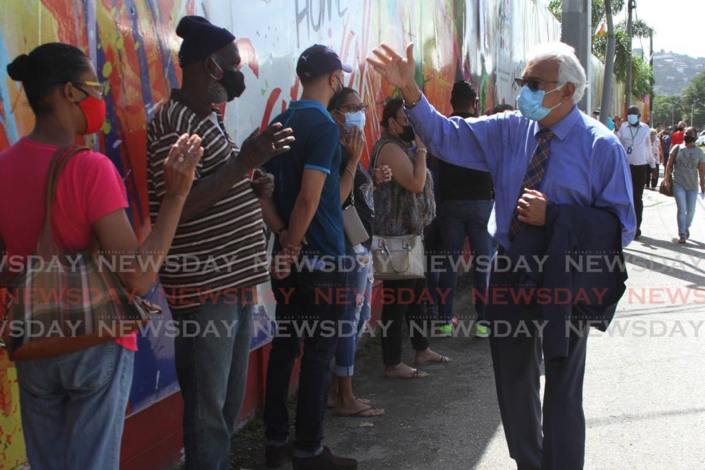 Health Minister Terrence Deyalsingh greets people waiting to receive the Sinopharm vaccine at the Paddock, Port of Spain on Friday. - Photo by Marvin Hamilton